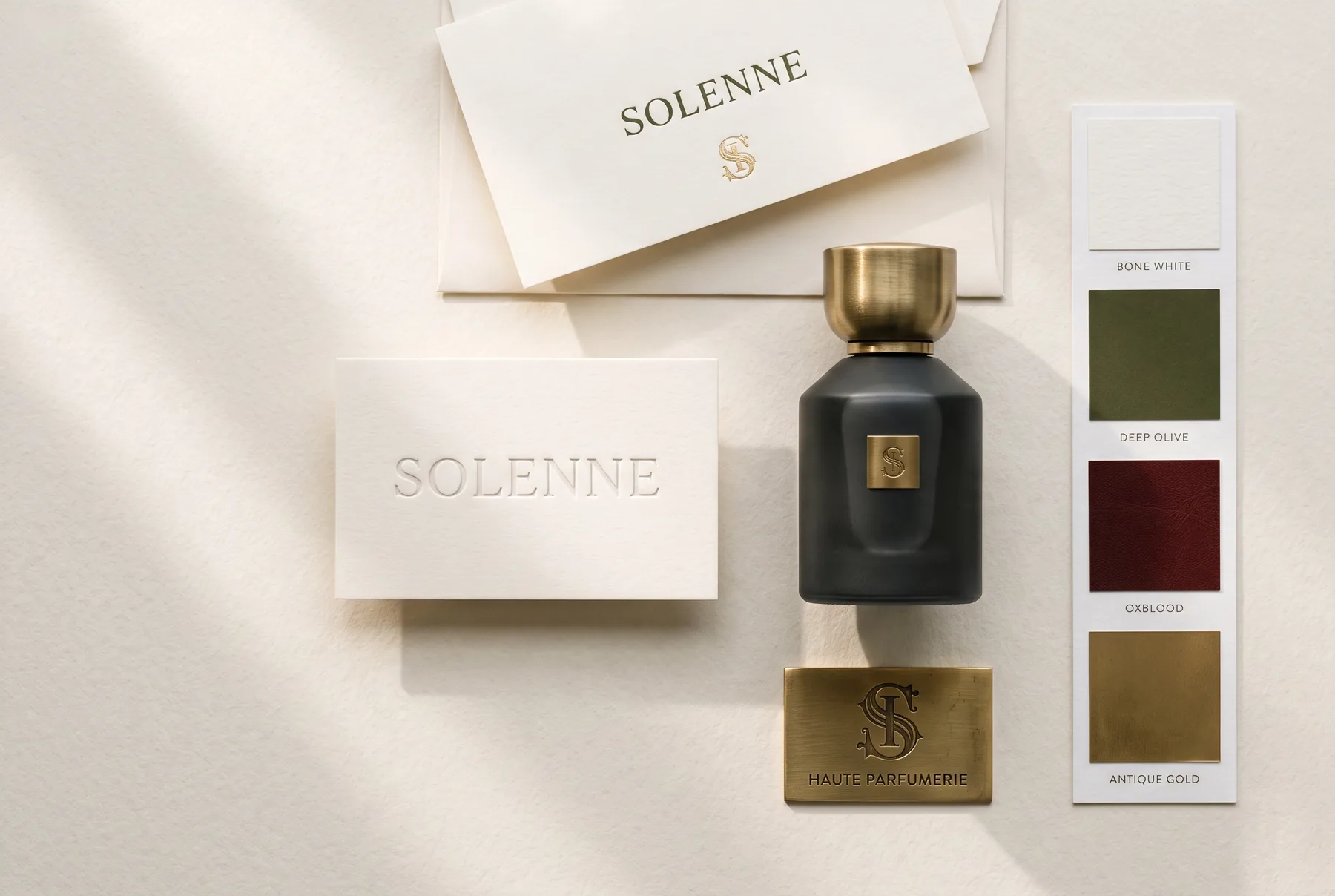 Solenne presentation board — debossed stationery, matte flacon with brass collar, etched brass plate and a four-colour material swatch card on cotton paper.