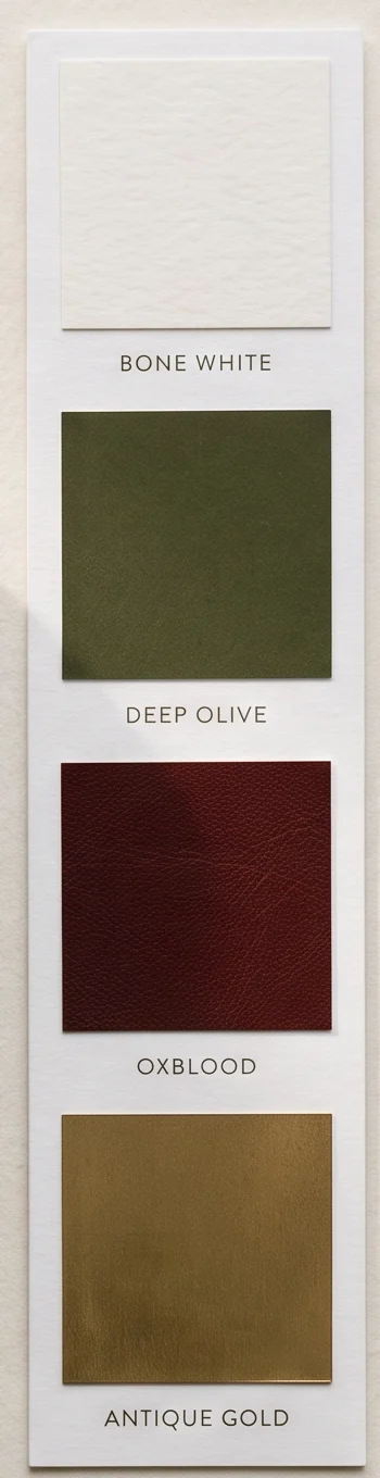 Material swatch card: bone white paper, deep olive cloth, oxblood leather and antique gold foil.